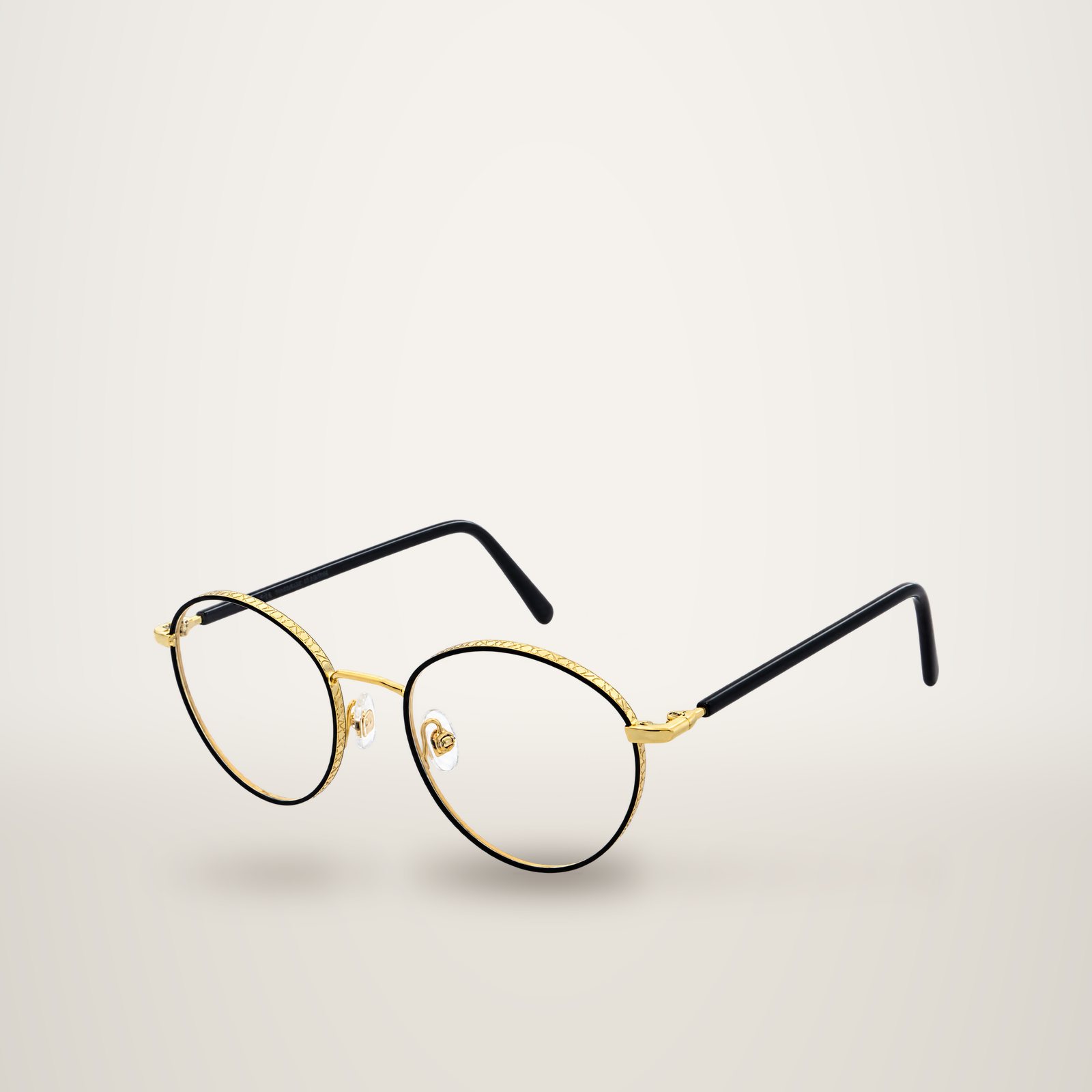 Paire de lunettes de vue rondes à fine monture noire et dorée ornée de motifs gravés, présentée sur fond blanc.