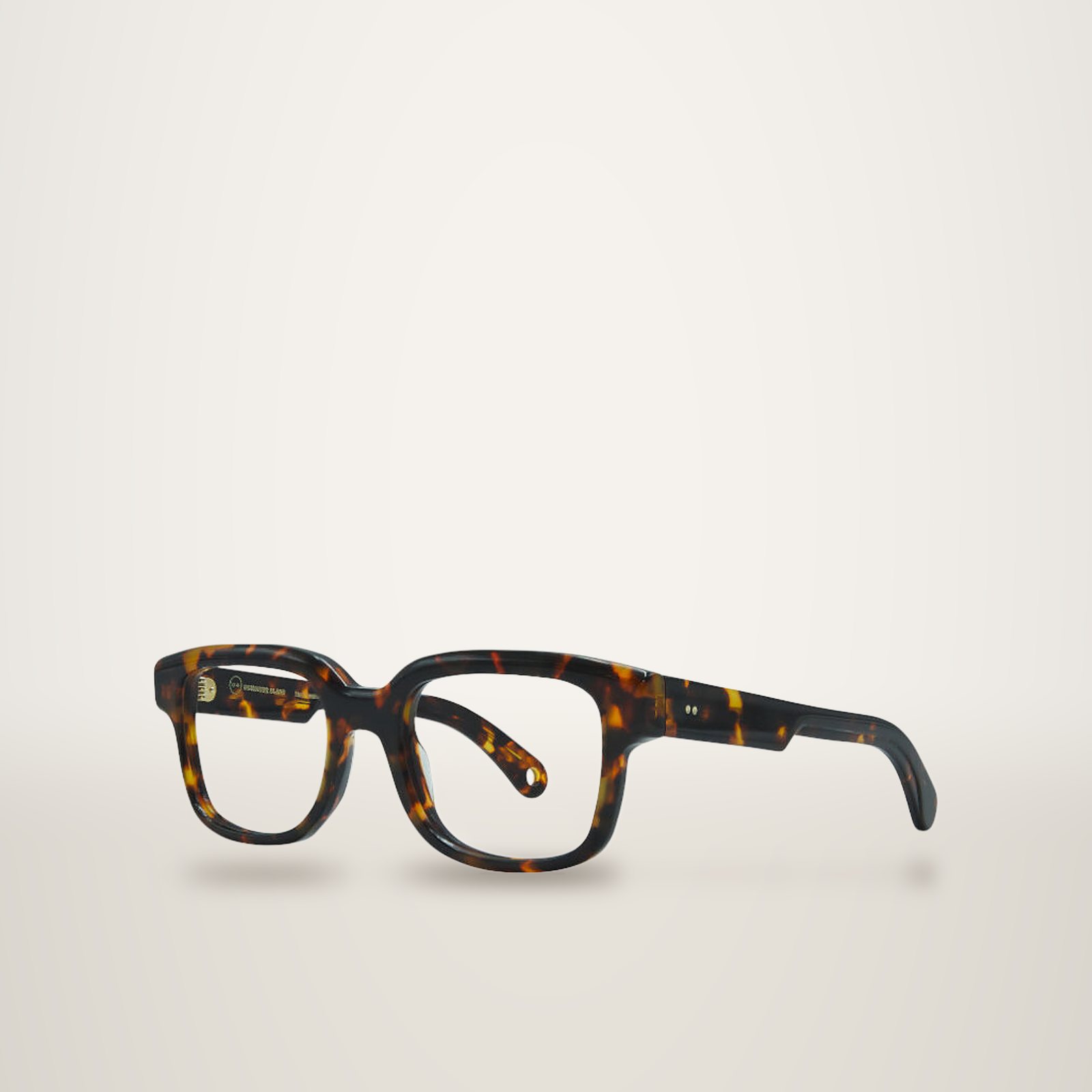 Monture de lunettes épaisse de forme carrée en acétate écaille de tortue brun et ambré, photographiée de trois quarts sur fond blanc.