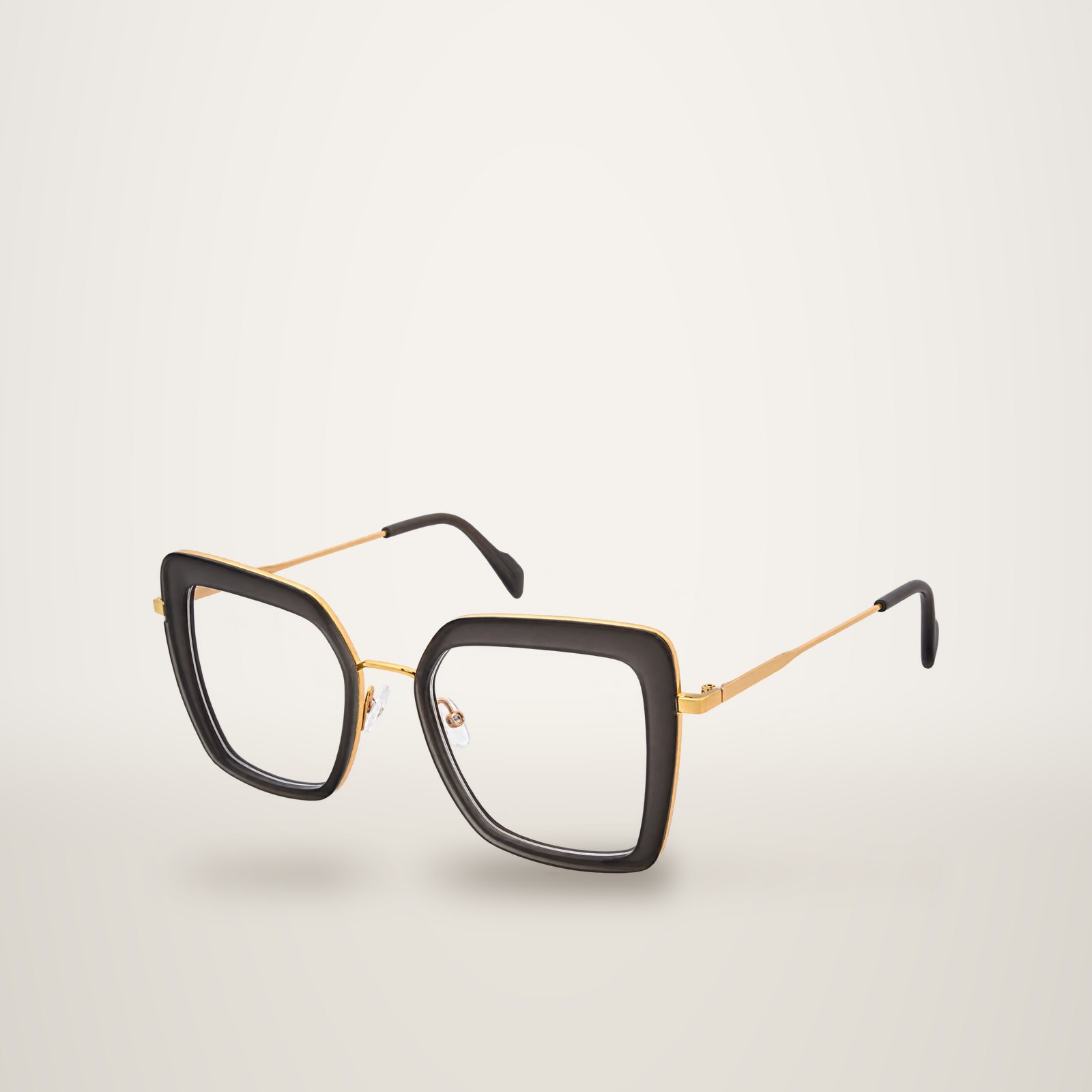 Monture de lunettes optiques oversize à forme carrée en acétate gris translucide, avec liseré et branches métalliques dorées, photographiée sur fond blanc.